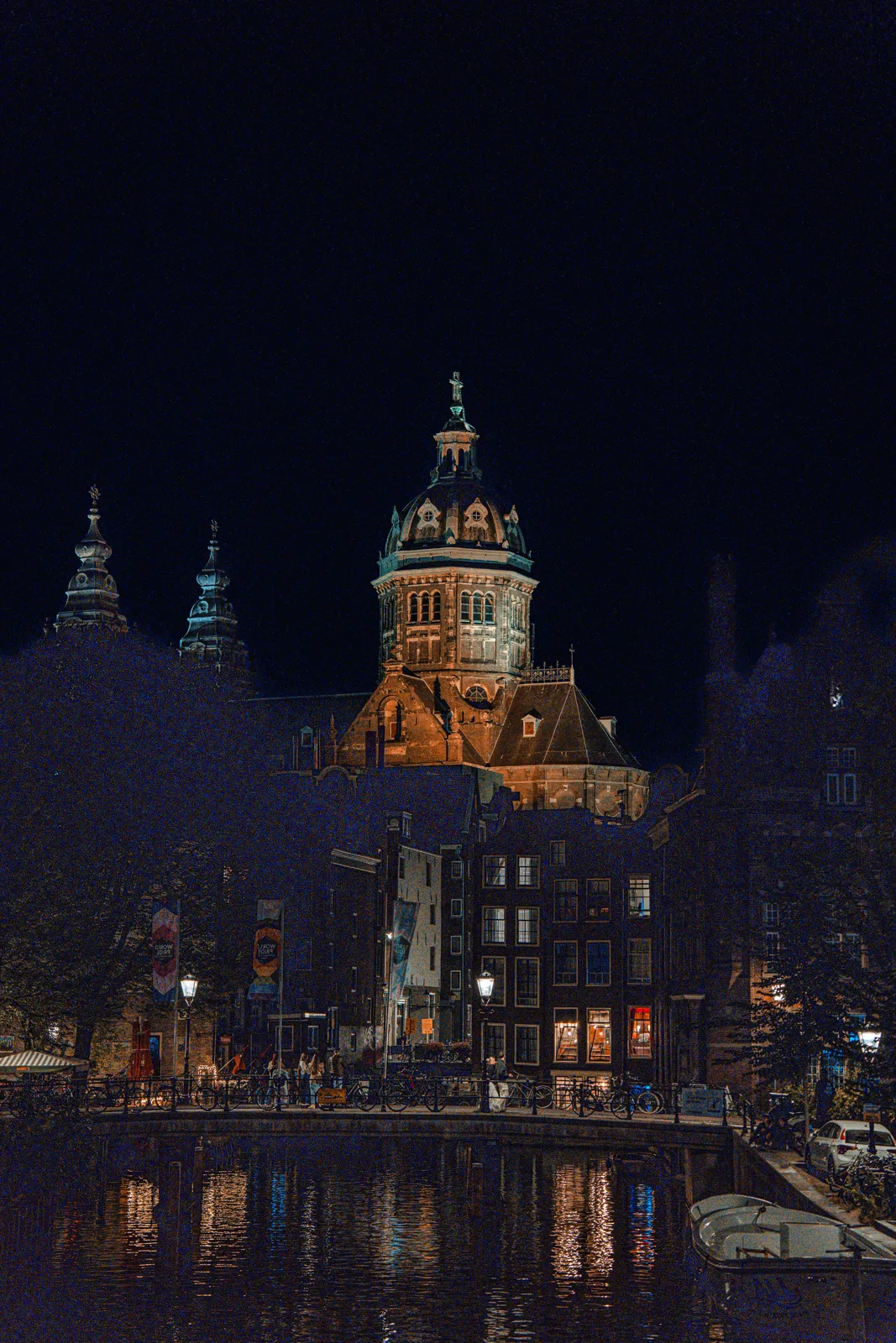 Torre iluminada de noche reflejada en un canal de Ámsterdam
