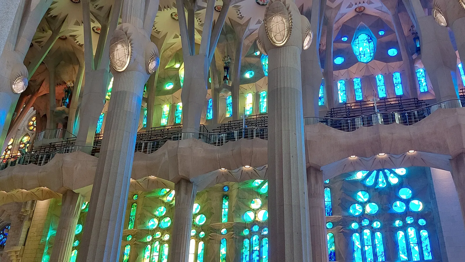 Interior de la Sagrada Familia con sus columnas arbóreas y vitrales azules y verdes de Gaudí