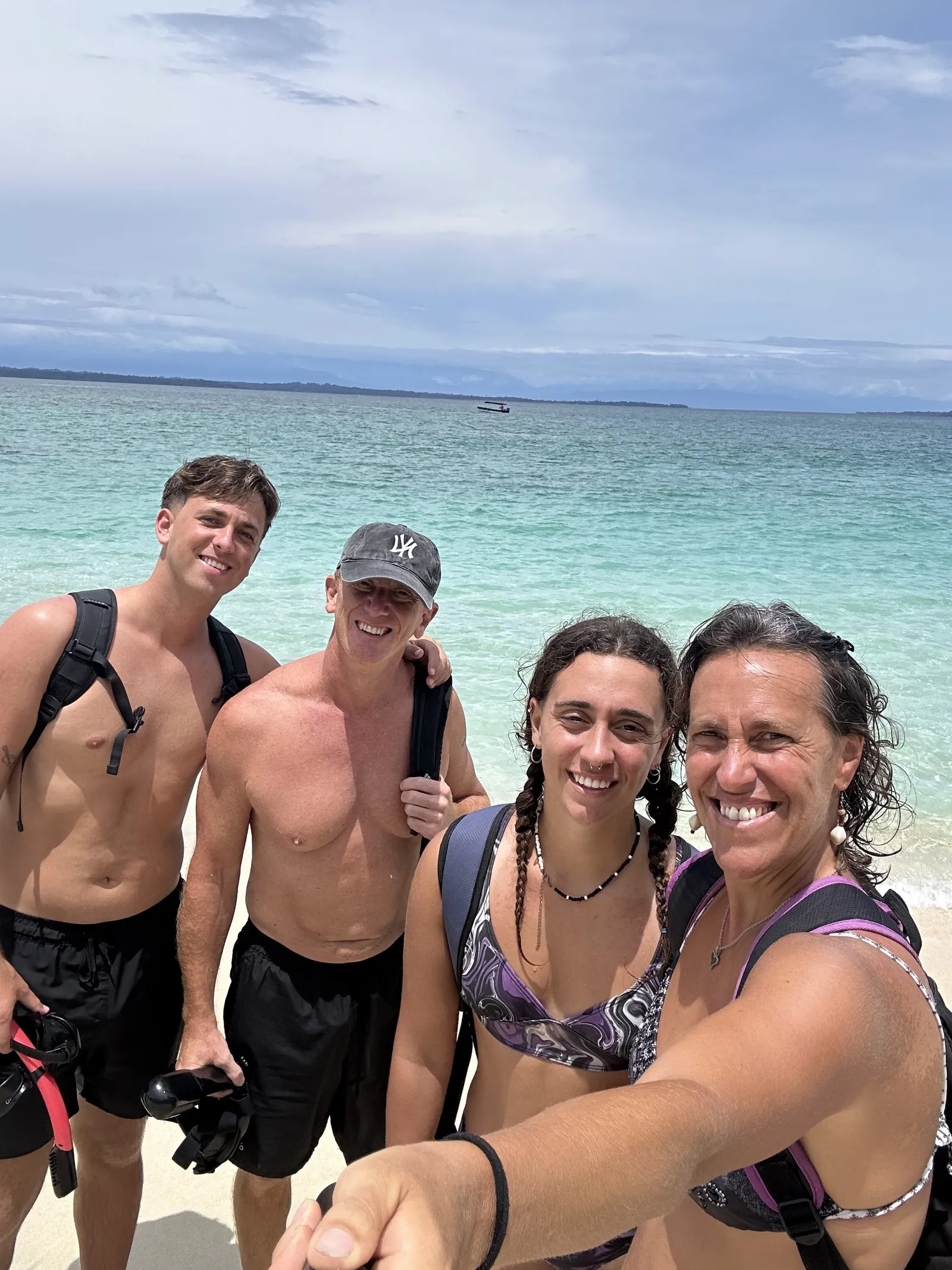 La familia sonriendo en la arena blanca de Cayo Zapatilla con el Caribe turquesa de fondo
