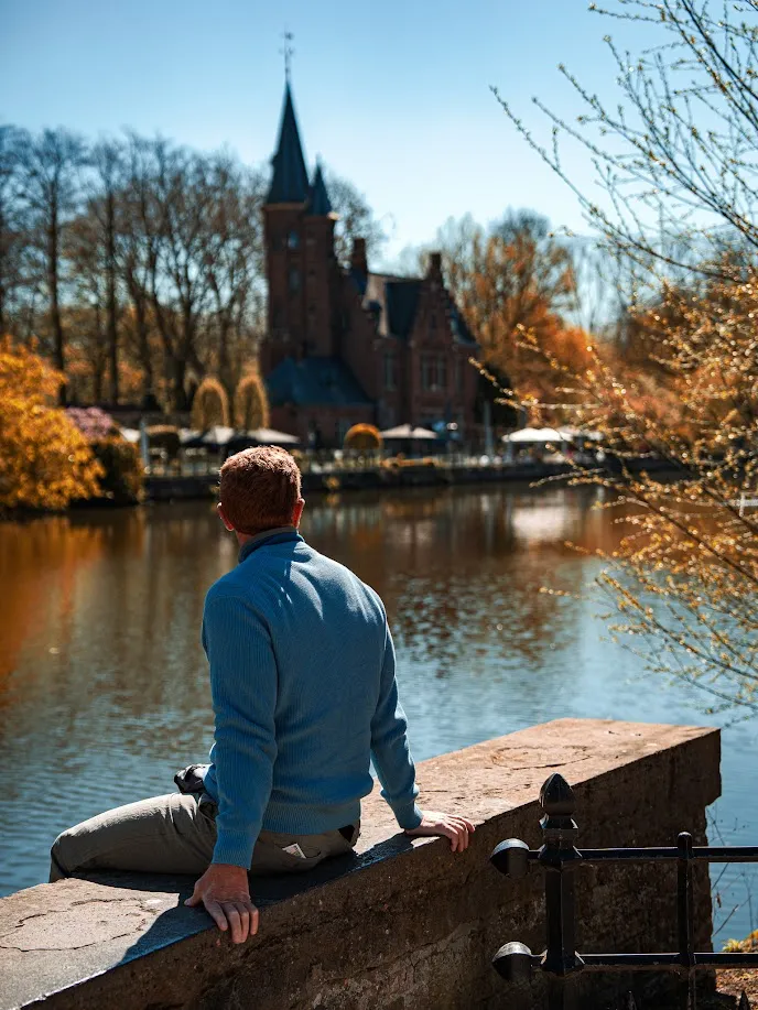 Diego sentado de espaldas contemplando el Lago del Amor (Minnewater) en Brujas