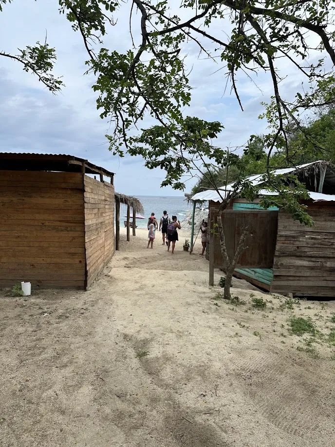 Entrada a la Playa del Tejón en Huatulco a través de un camino de arena entre construcciones de madera