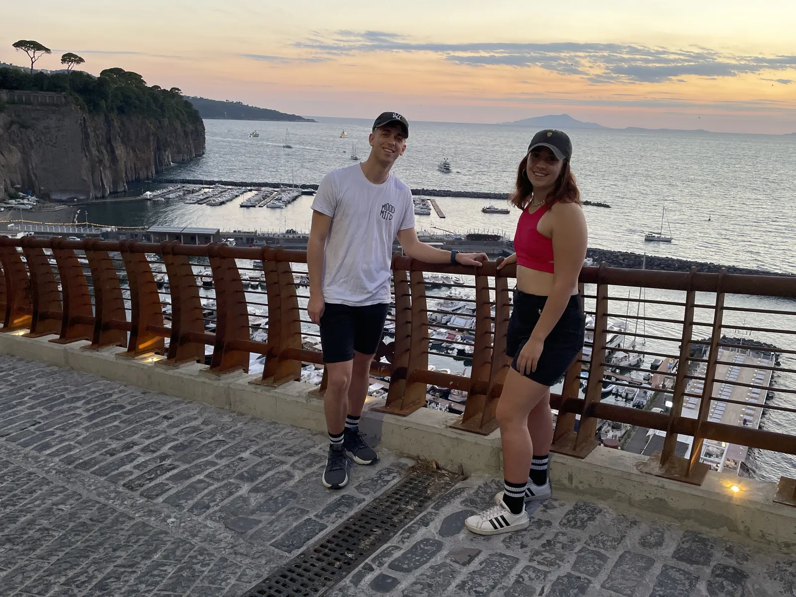 Dos jóvenes en el mirador sobre el puerto de Piano di Sorrento al atardecer