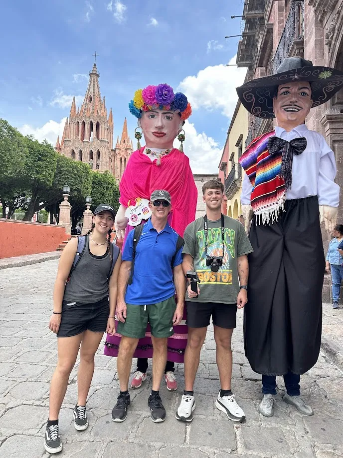La familia con las mojigangas de Frida Kahlo y el Charro frente a la Parroquia de San Miguel Arcángel