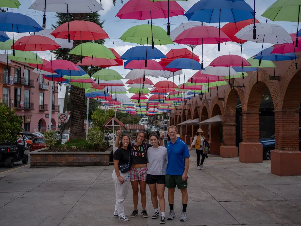 La familia bajo una instalación de paraguas de colores en el centro de Metepec