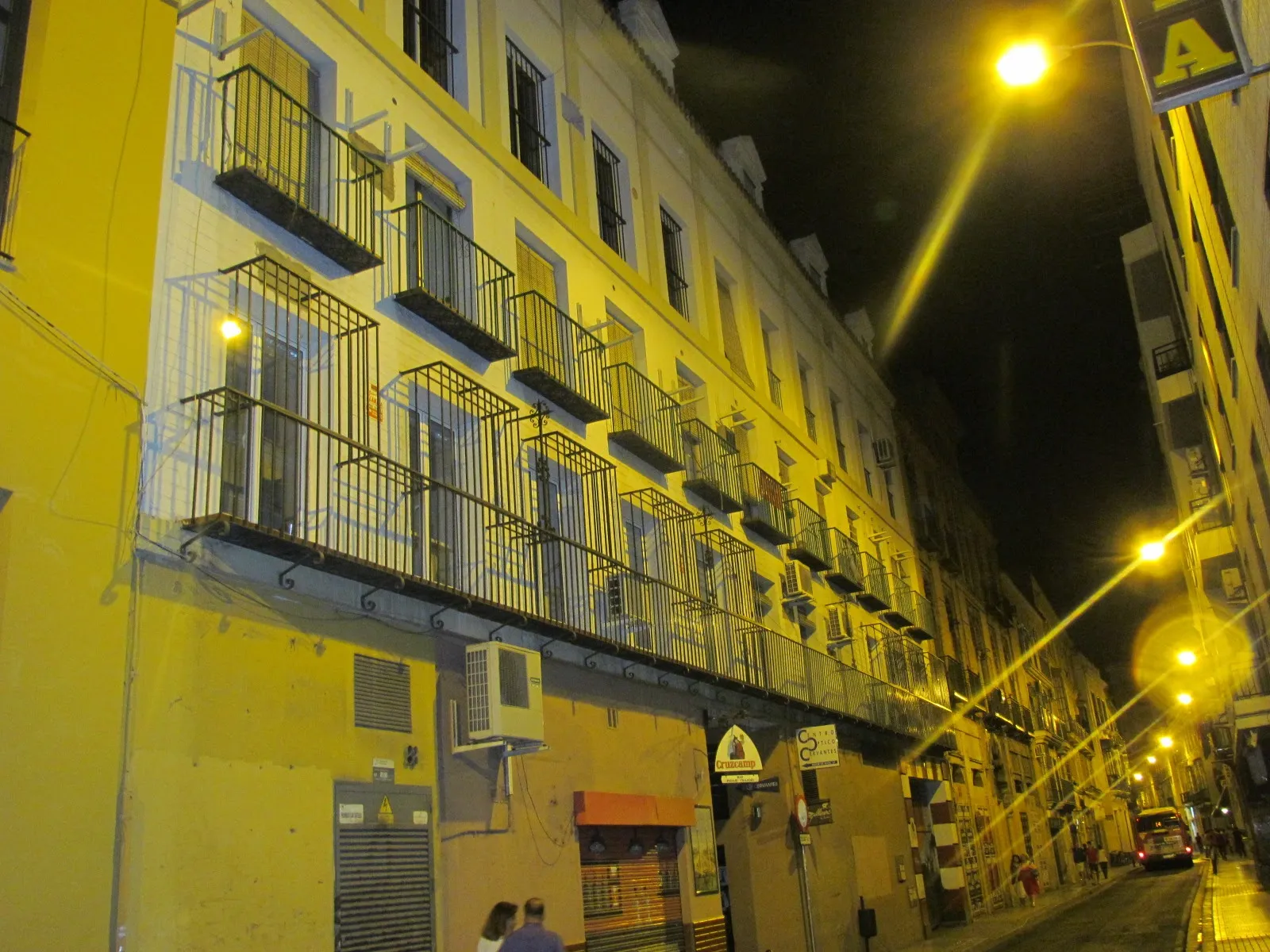 Calle del Barrio de la Macarena de noche, con balcones de hierro y fachadas amarillas, Sevilla