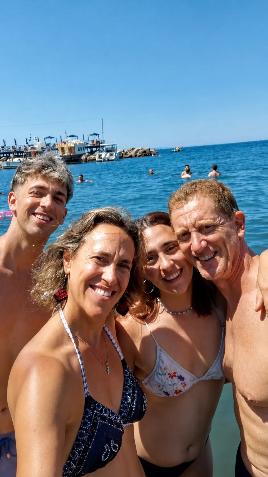 La familia en el mar de la Marina Piccola de Sorrento bajo el sol de julio