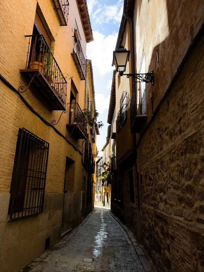 Callejón medieval de Toledo con faroles y balcones de piedra
