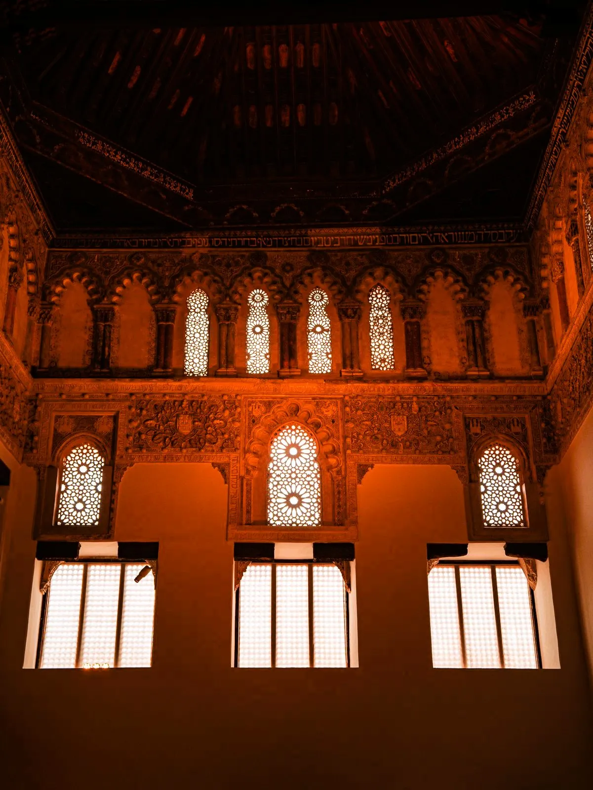 Interior de la Sinagoga del Tránsito en Toledo, con arcos mudéjares iluminados en naranja